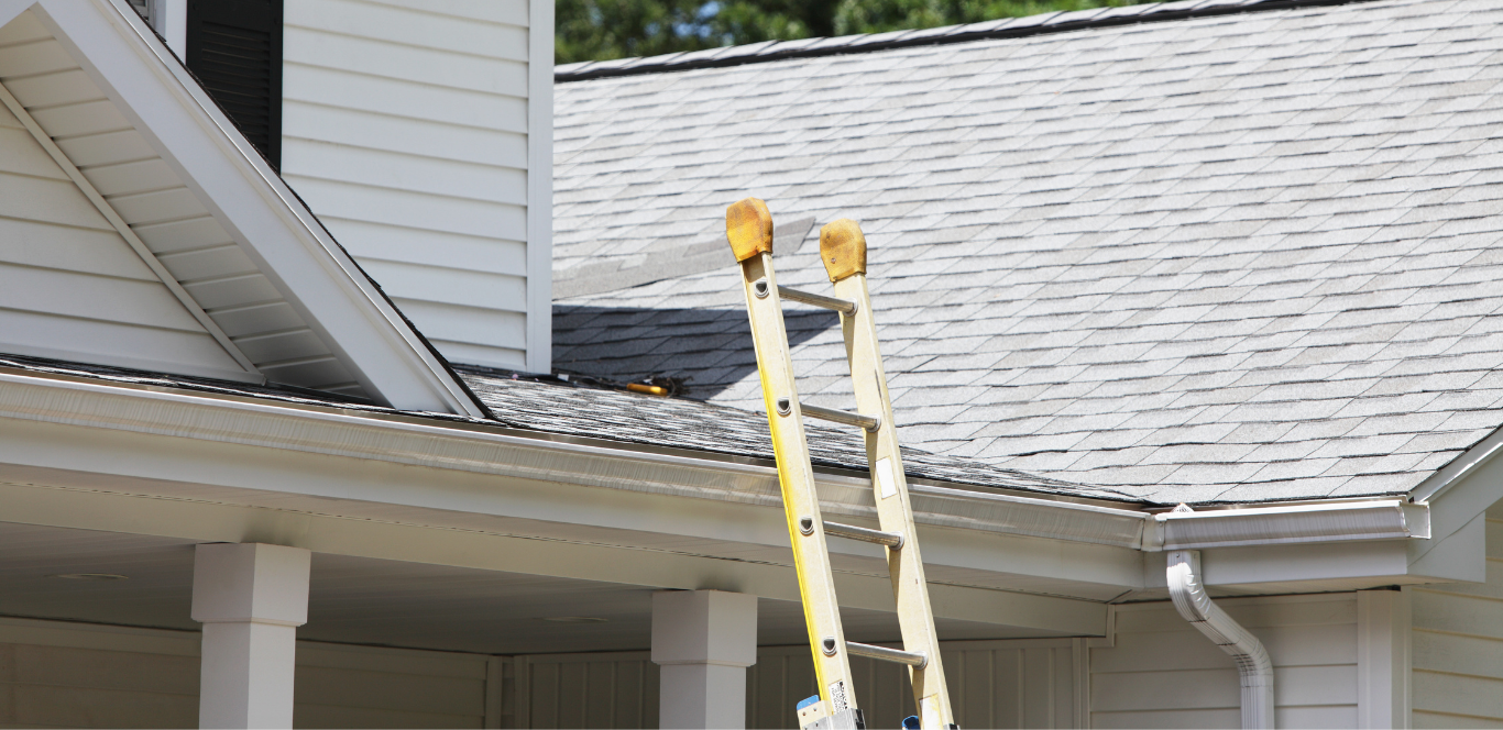 A ladder is sitting on the roof of a house.