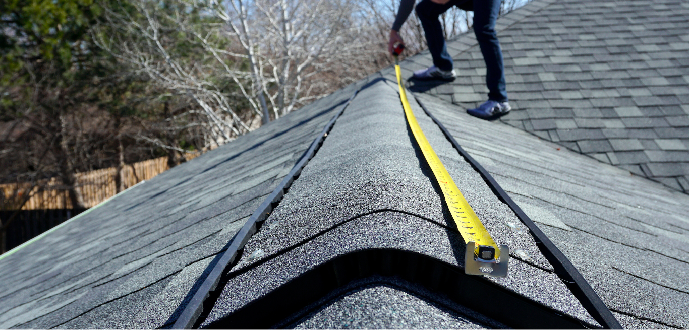 A man is measuring a roof with a tape measure.