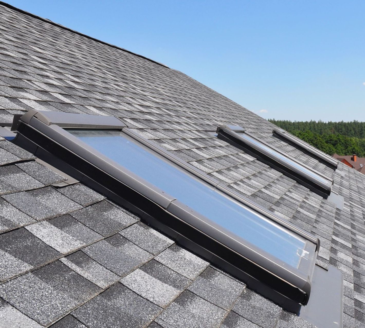 A roof with two skylights on it and a blue sky in the background