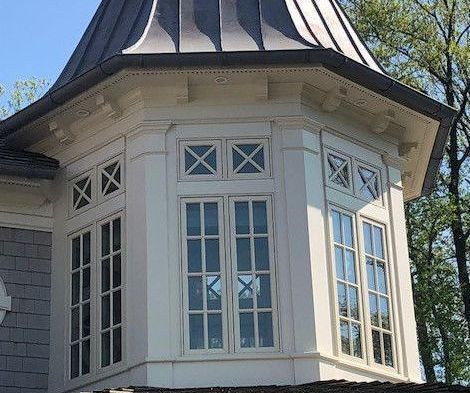 A white house with a copper roof and a bay window.