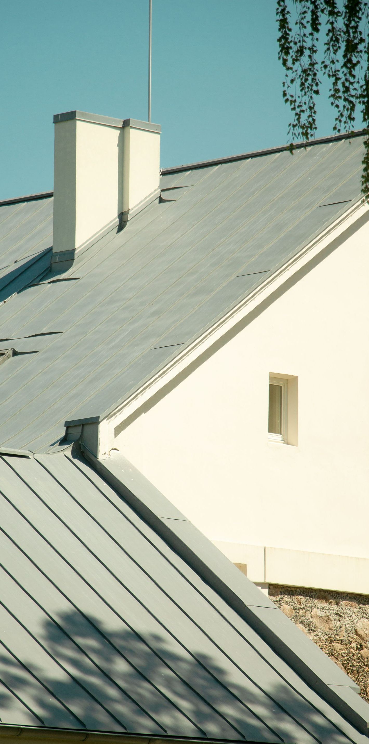A white house with a metal roof and chimneys