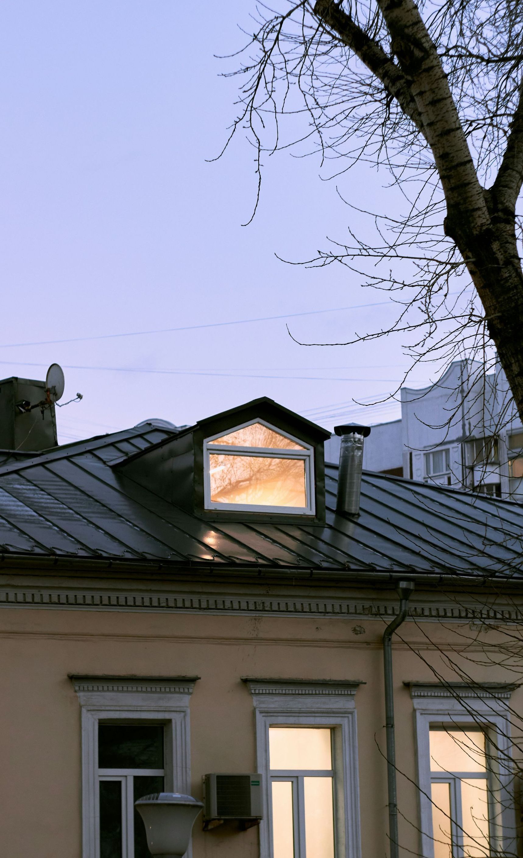 A house with a window on the roof and a tree in the background.