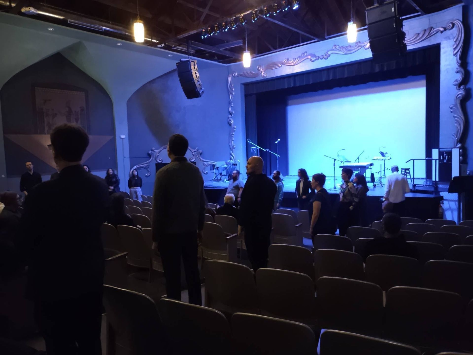 A group of people standing in front of a stage in an auditorium