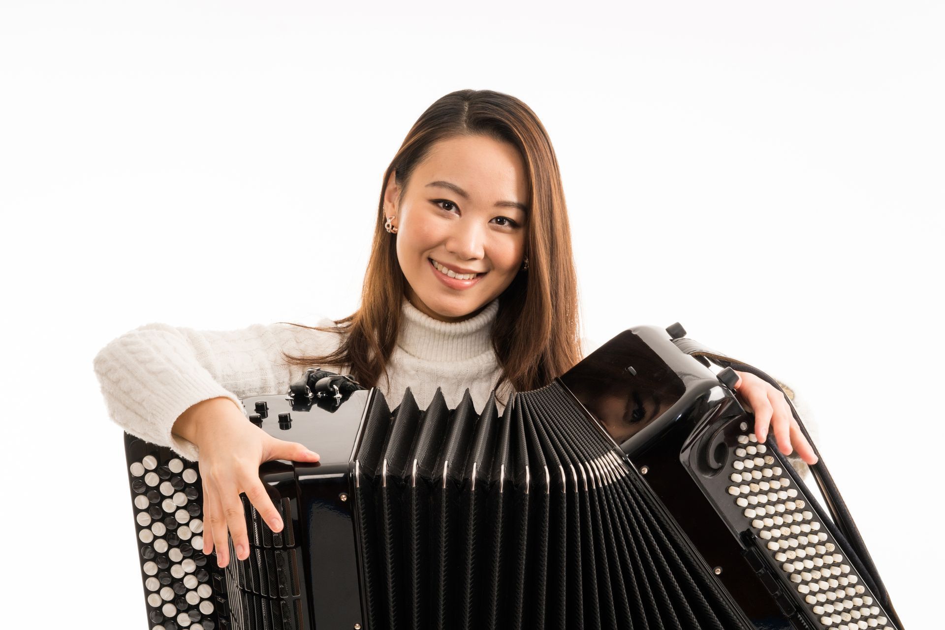 A woman is holding an accordion and smiling.