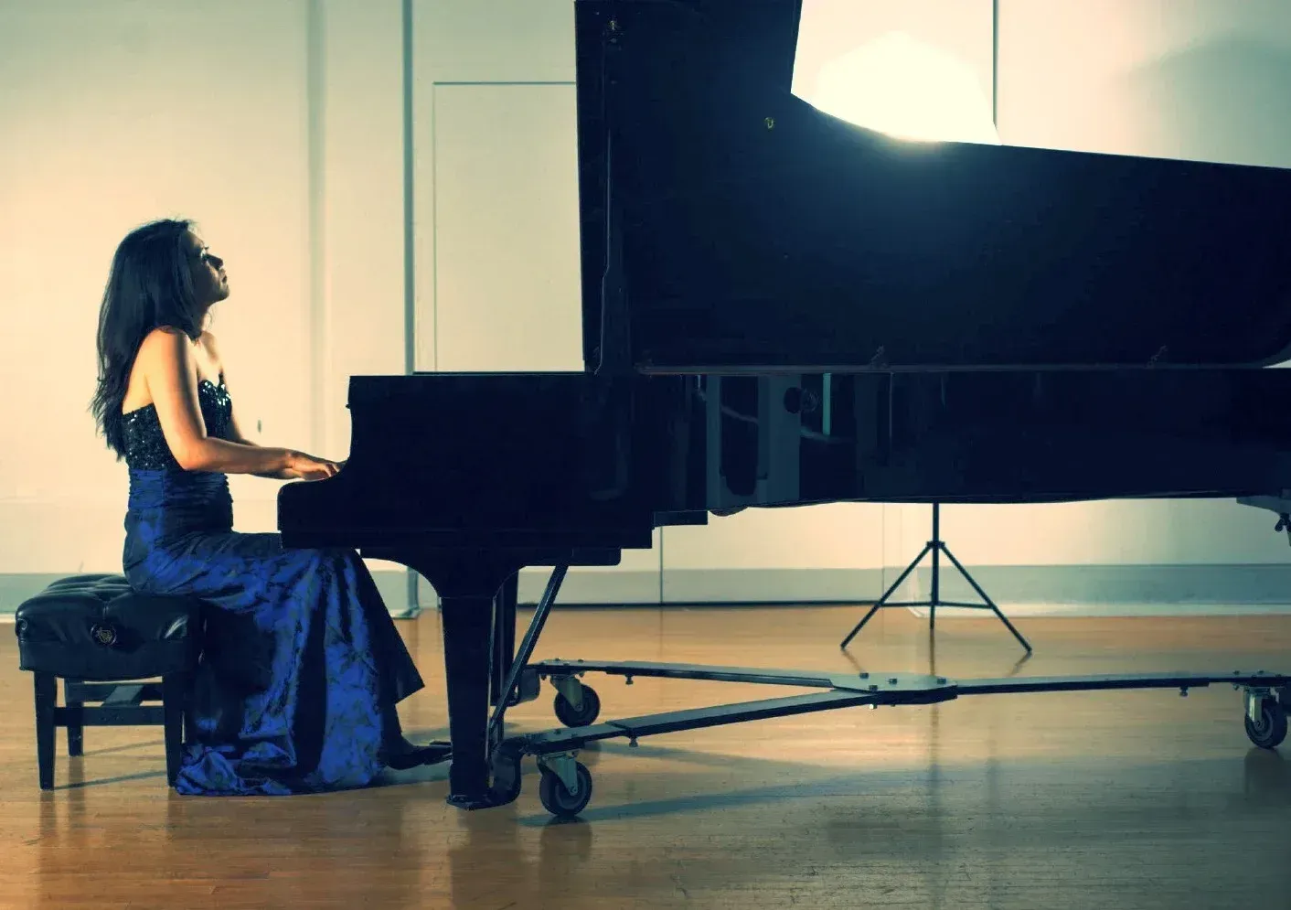 A woman in a blue dress is playing a piano
