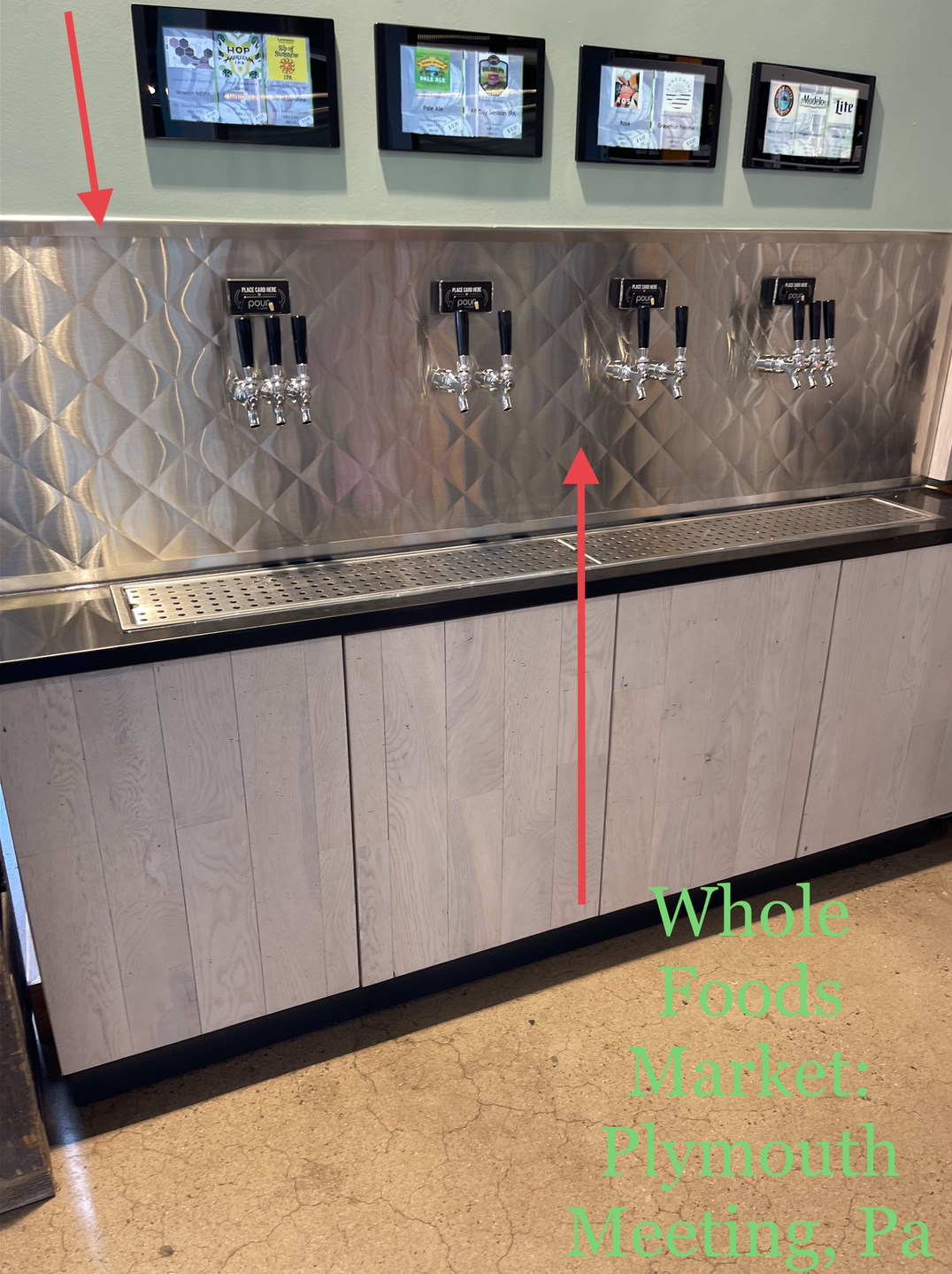 Self-serve beverage station with four drink dispensers and a wooden cabinet below.