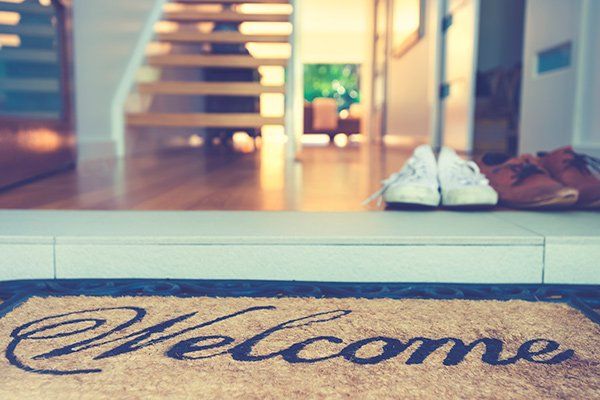 A welcome mat in front of an open door looking into a house.