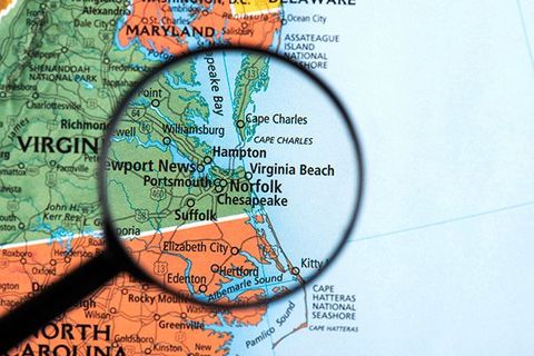 A magnifying glass centered over Norfolk, VA on a map.
