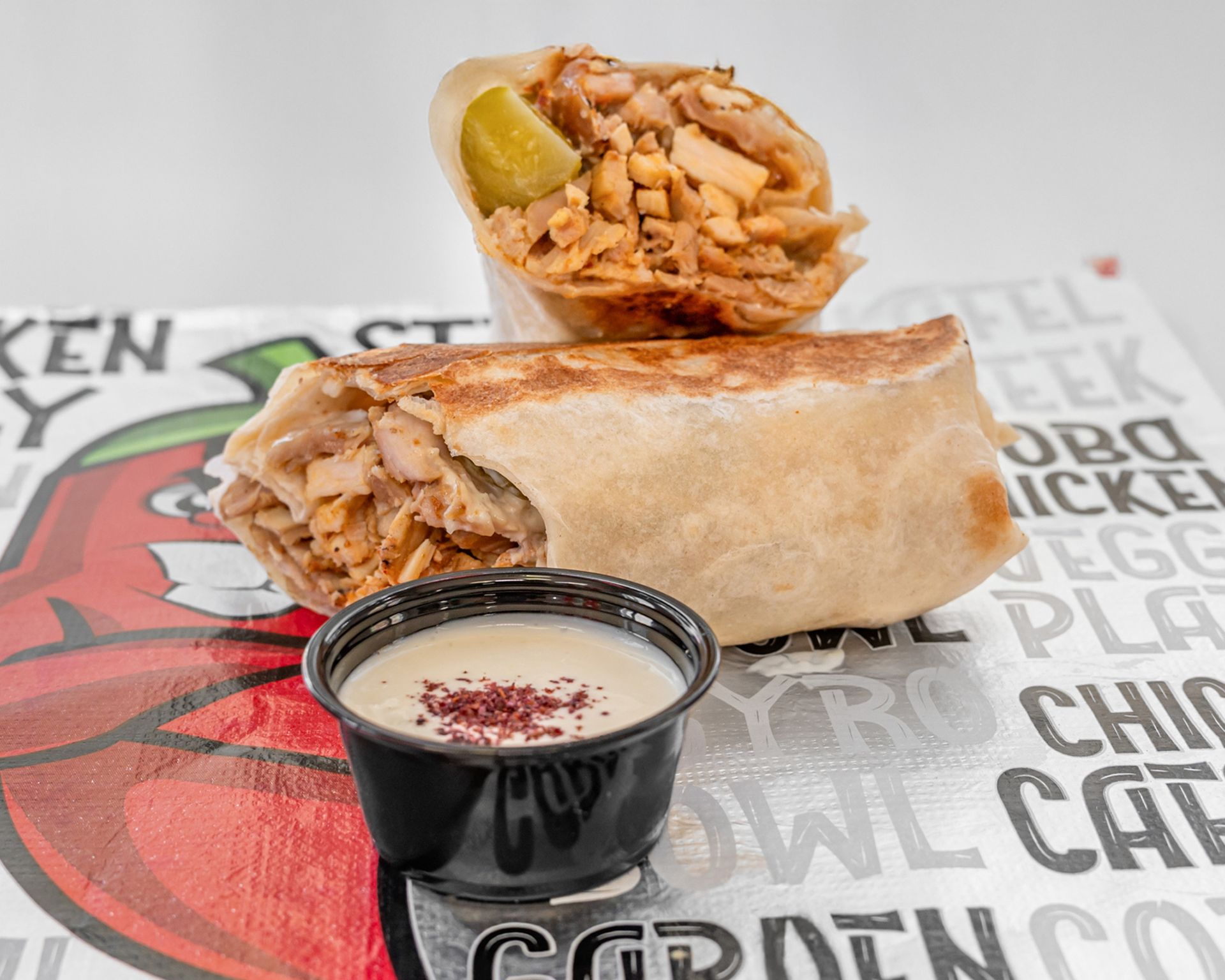 Two shawarma sandwiches are sitting on top of each other on a wooden table.