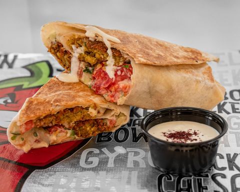 Falafel wrap cut in half, with sauce, on a table.