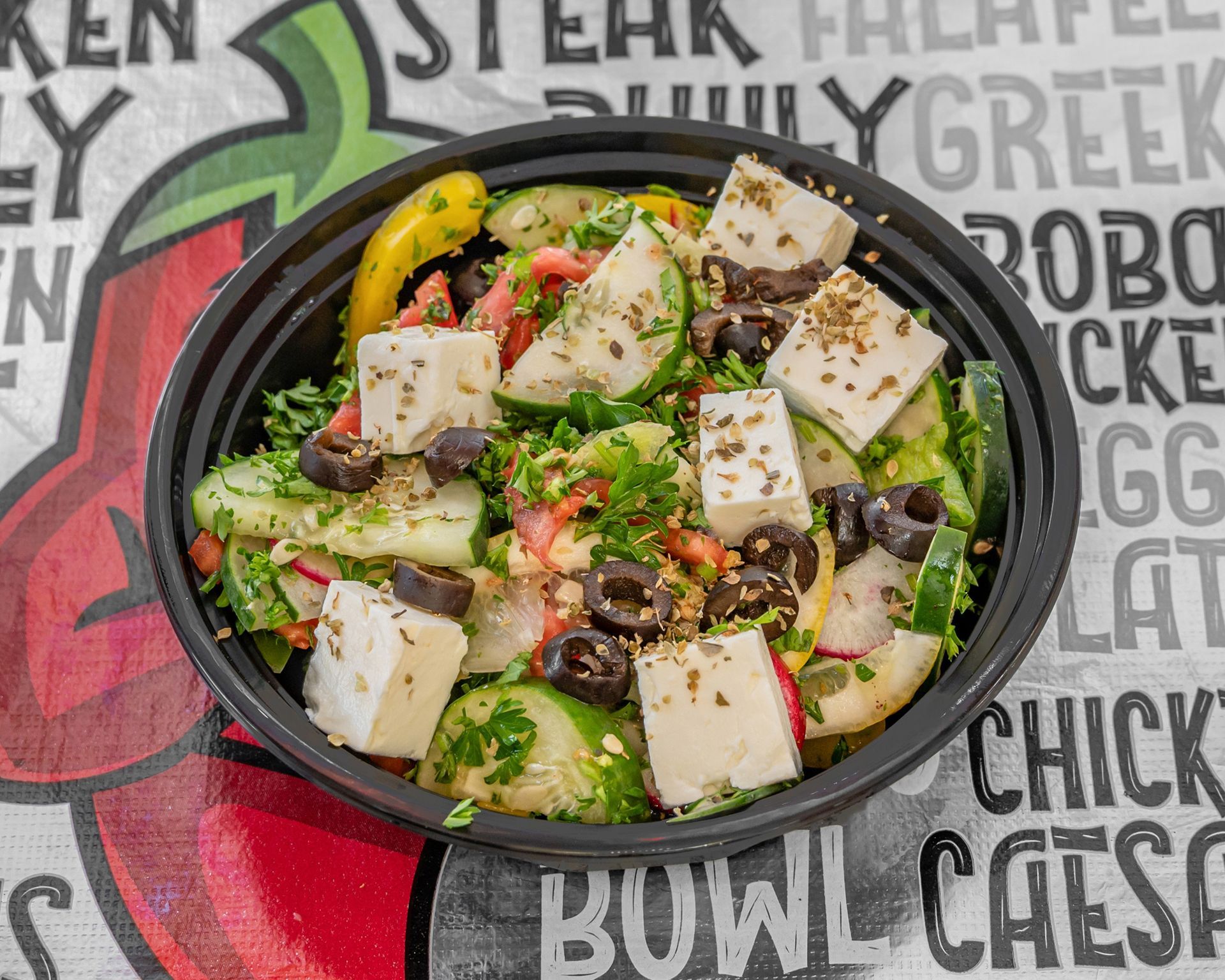 A gyro sandwich with meat , lettuce , tomatoes and onions on a wooden table.