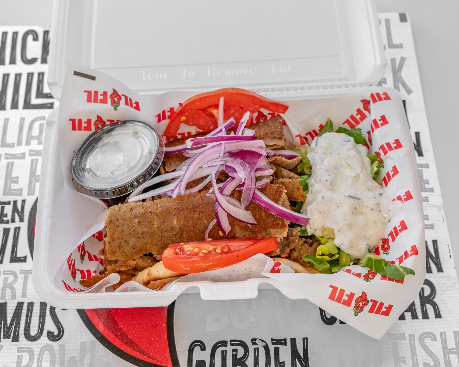 A tray of gyros and french fries on a table.