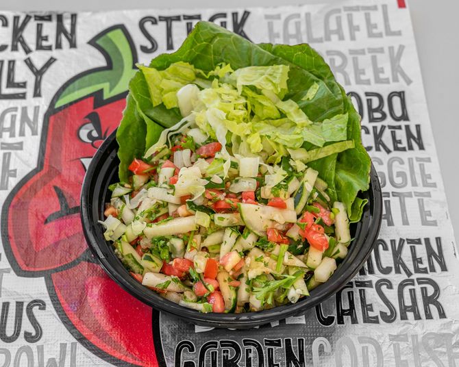 Salad bowl with chopped vegetables and lettuce on a white background.
