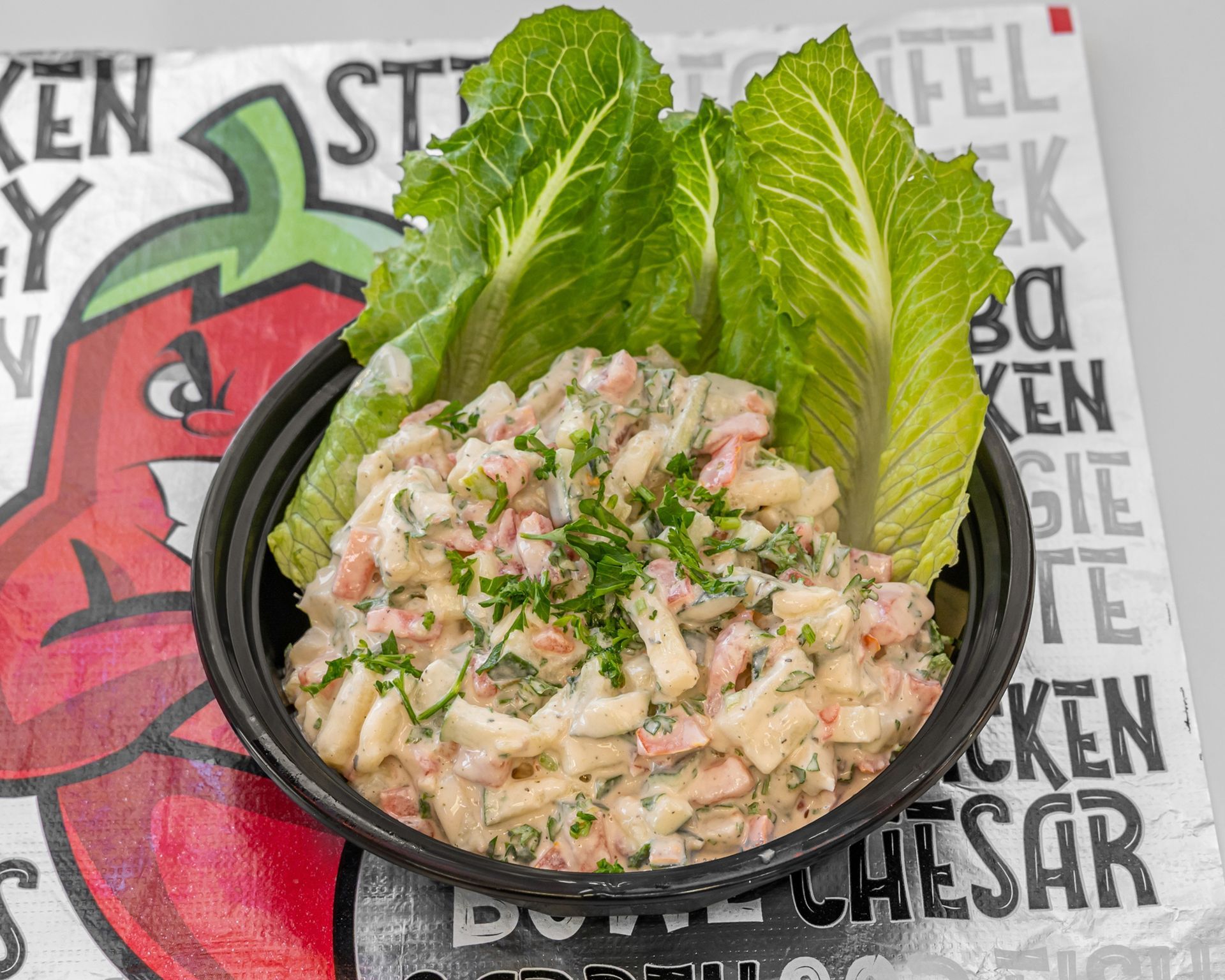 A fried chicken sub sandwich with lettuce , pickles and ranch dressing on a bun.