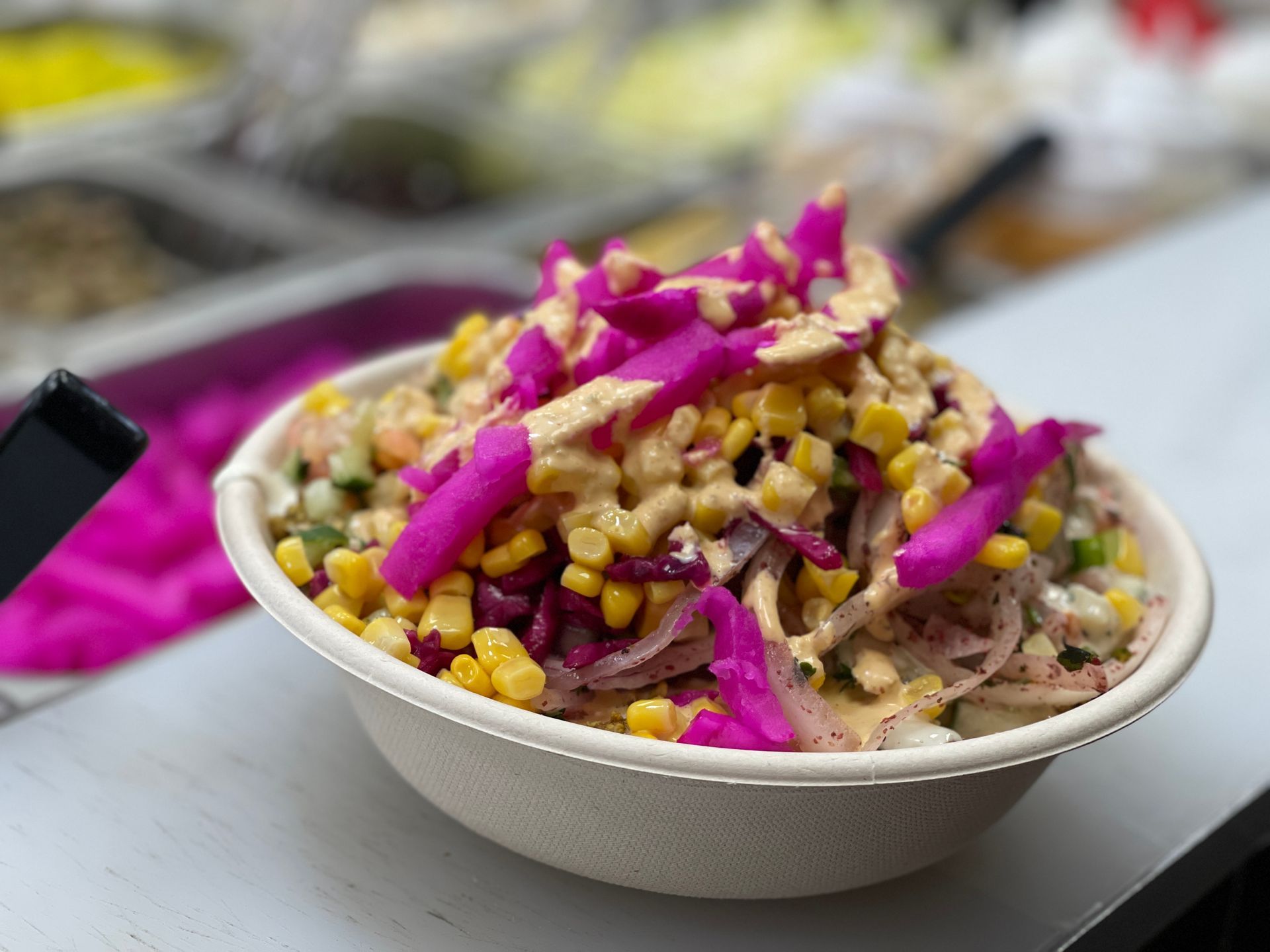 A bowl of food with corn , cabbage and onions on a table.