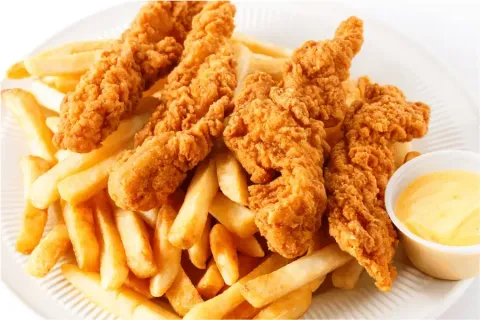 Chicken tenders and french fries with dipping sauce on a plate.