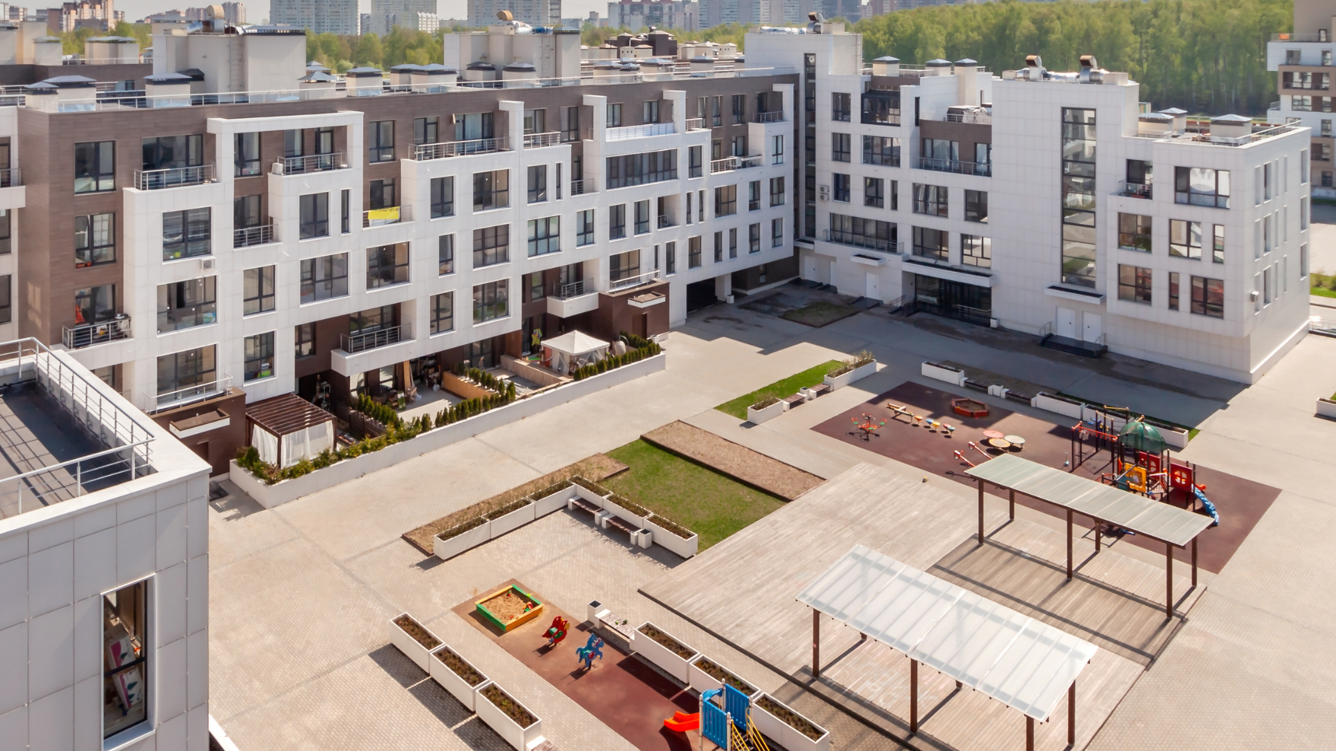 Modern apartment complex courtyard with playground and benches.