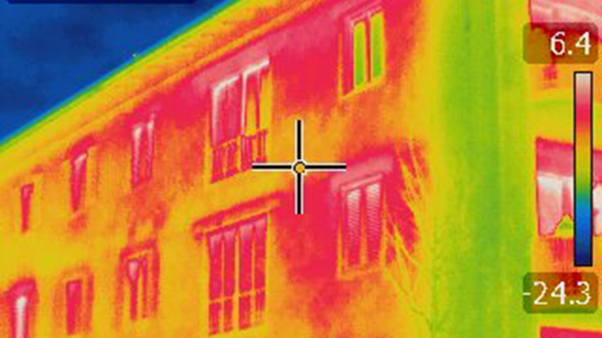 Thermal image of building facade, windows showing temperature differences: warm yellow to cool blue.