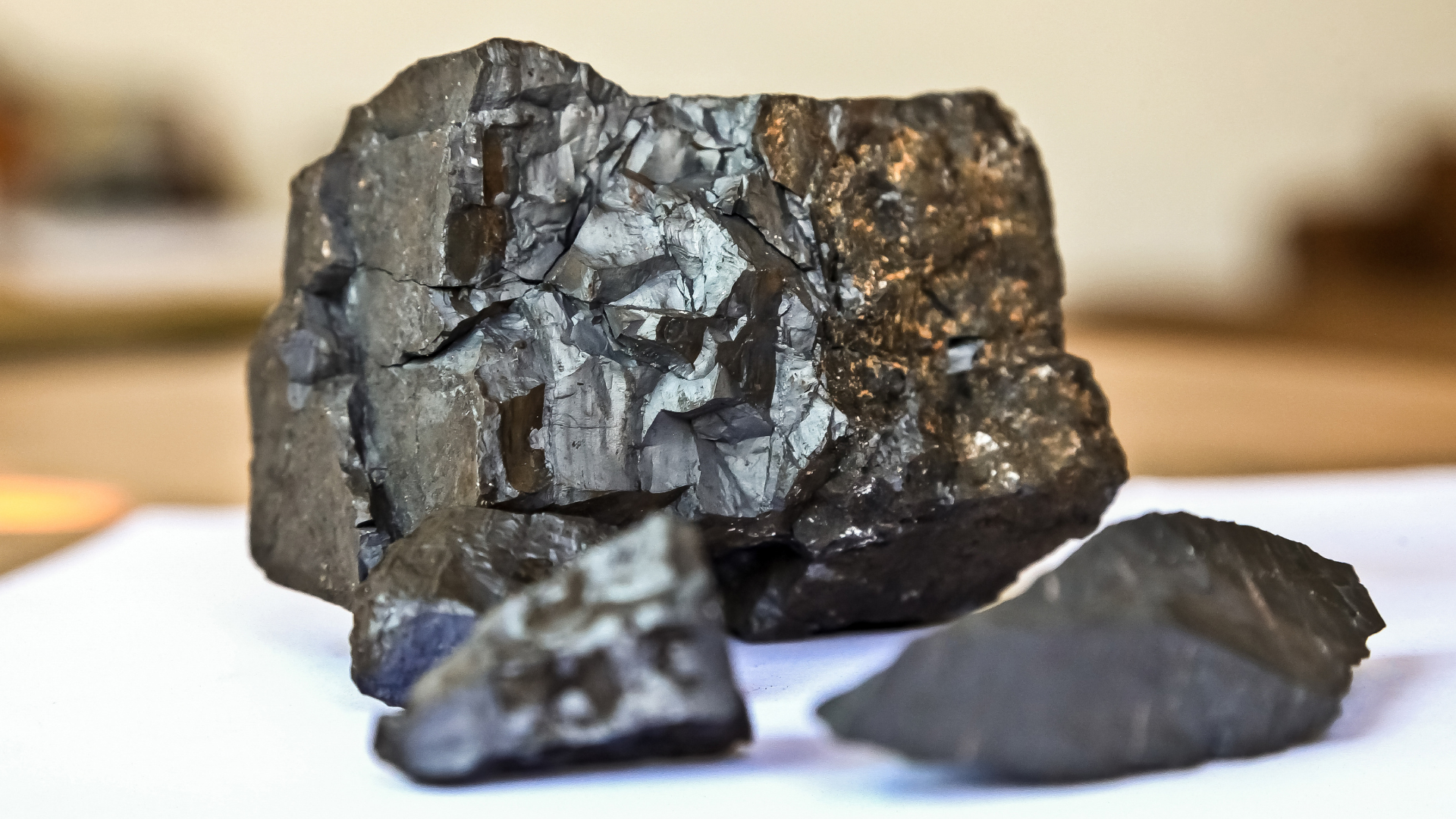 Chunks of black coal, broken and jagged, on a white surface.