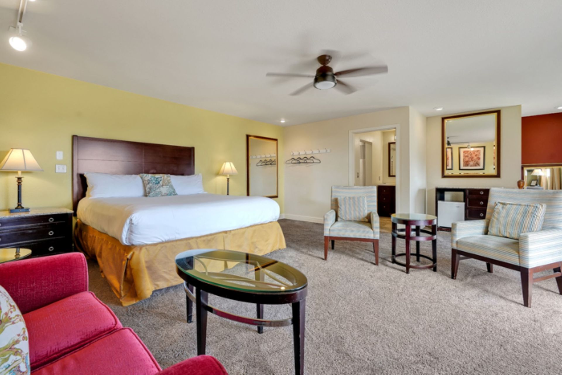 A hotel room with a king size bed and a ceiling fan