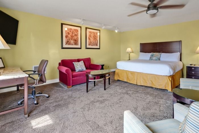 A hotel room with a king size bed and a red couch