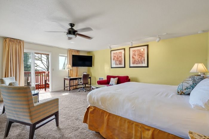 A hotel room with a king size bed , chairs , desk and television.