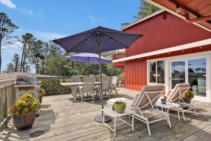 A wooden deck with chairs and umbrellas on it