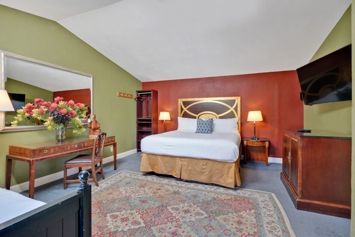 A hotel room with a king size bed , desk , chair and television.