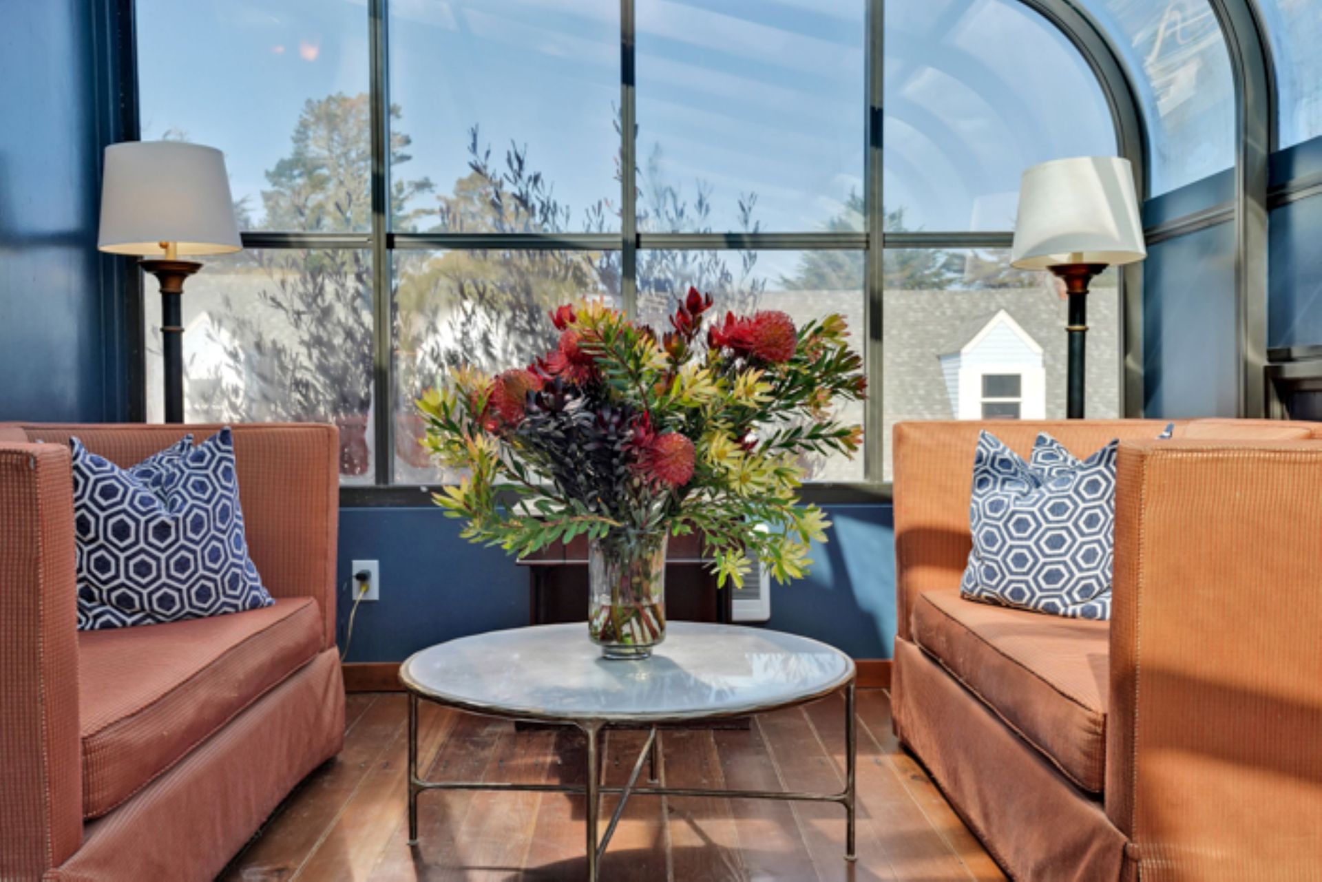 A living room with two chairs and a table with a vase of flowers on it