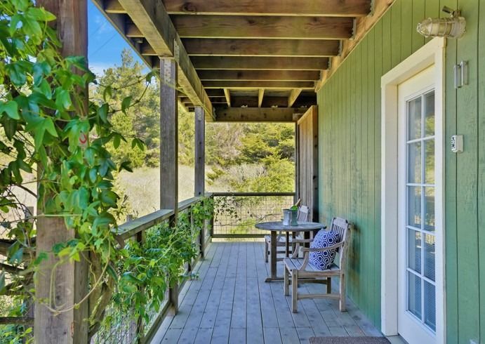 A green house with a porch with a table and chairs