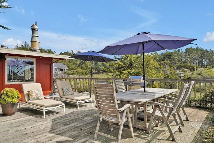 A wooden deck with a table and chairs and umbrellas.