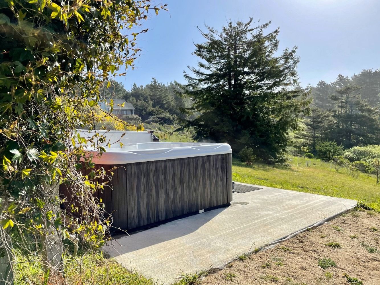 A hot tub is sitting on a concrete patio in the middle of a field.
