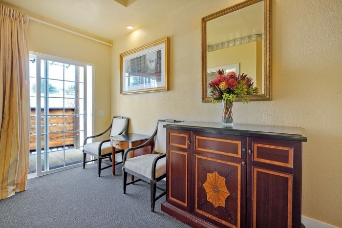 A room with two chairs and a dresser with a vase of flowers on it.