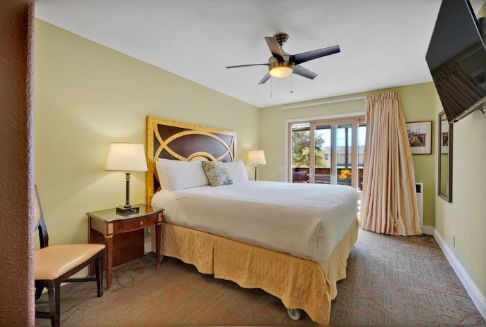 A hotel room with a king size bed and a ceiling fan