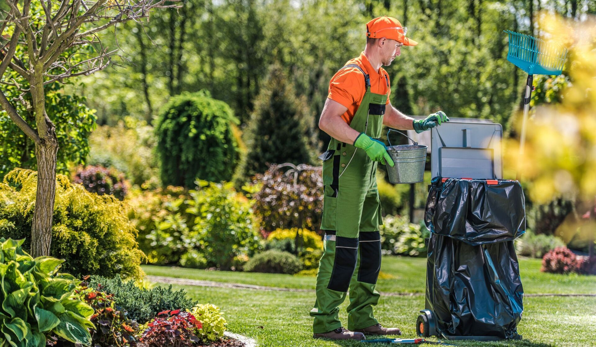 A man is standing next to a trash can in a garden.