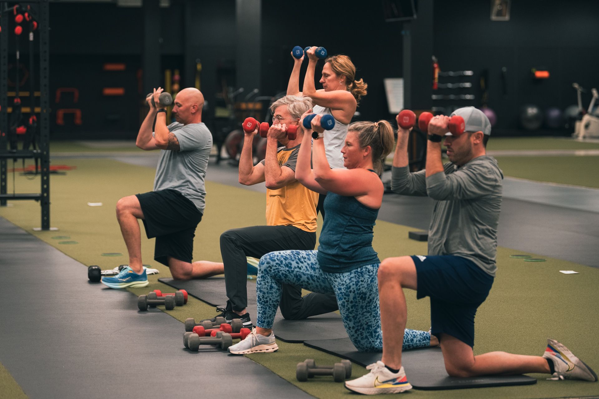 A group of people are lifting dumbbells in a gym.