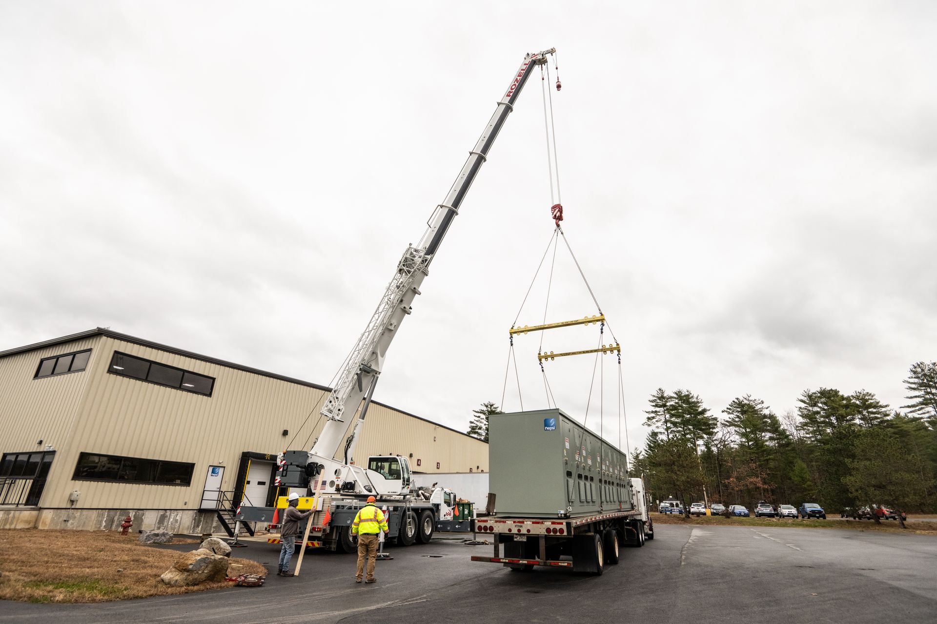 A truck is being lifted by a crane in front of a building.