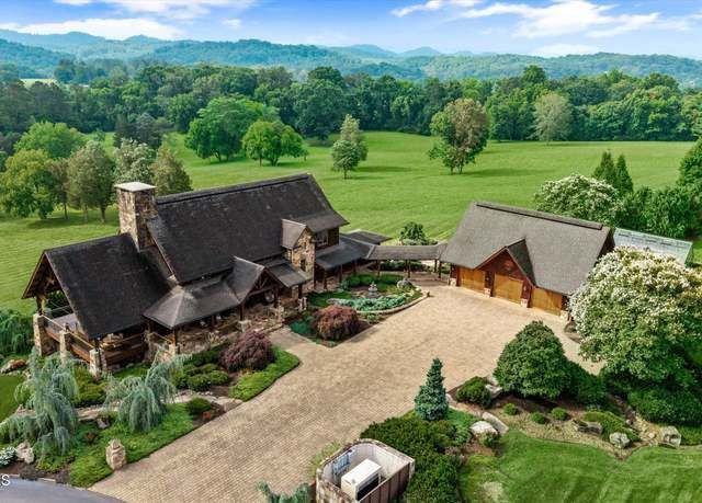 An aerial view of a large house in the middle of a field surrounded by trees.
