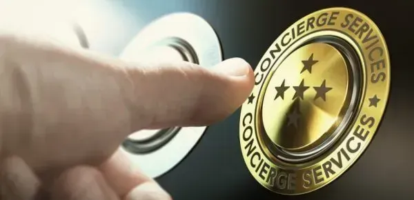 A person is holding a gold badge that says concierge services