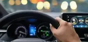 A person is driving a car with their hands on the steering wheel.