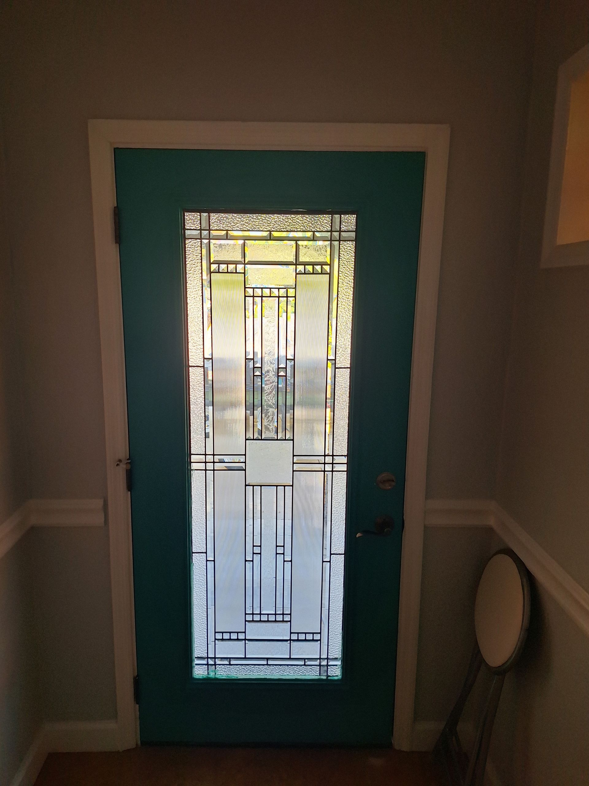 A blue door with a stained glass window in a hallway.