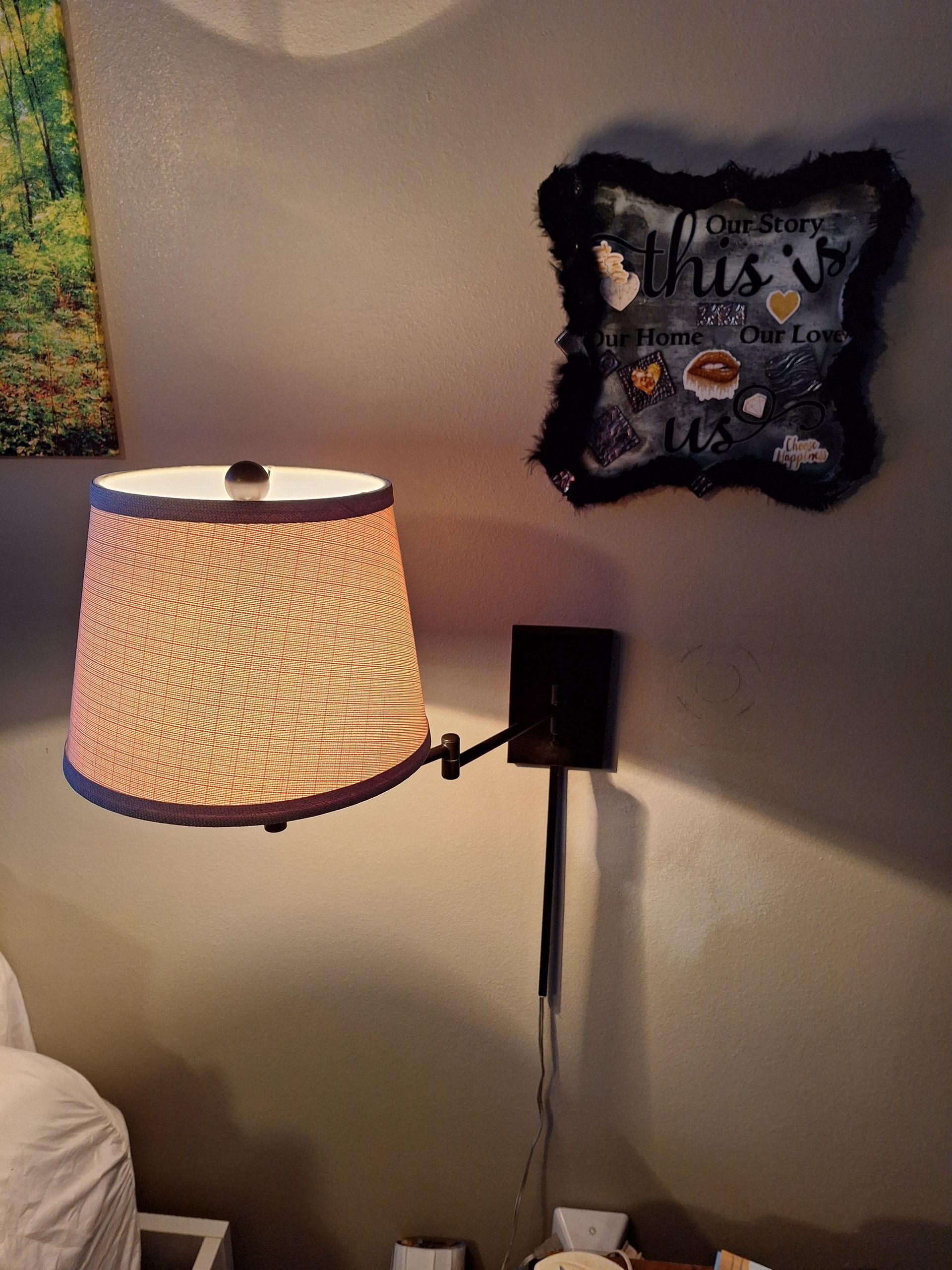 A lamp is hanging on a wall next to a framed picture that says 
