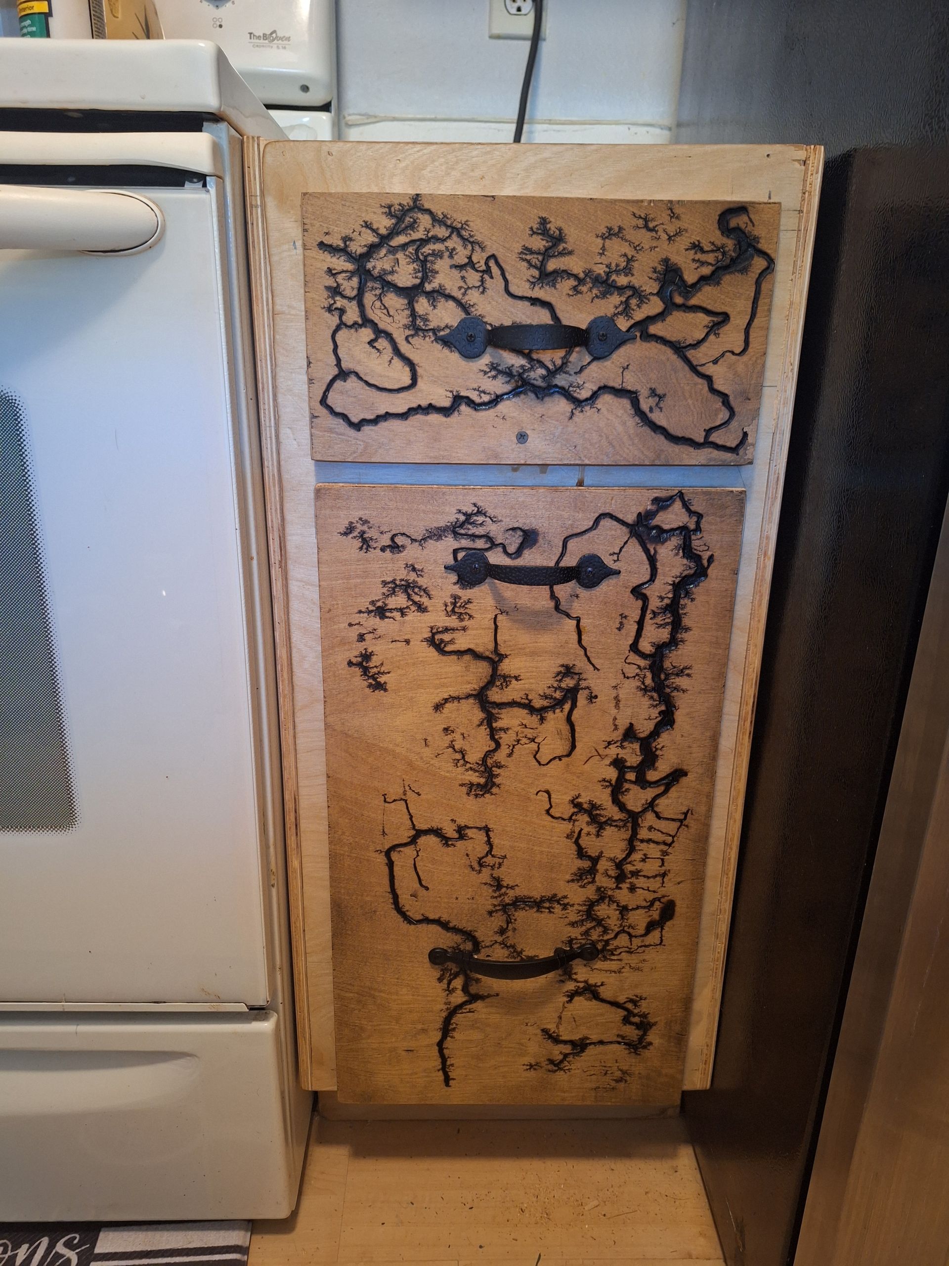 A wooden cabinet with a drawing on it is next to a white stove.