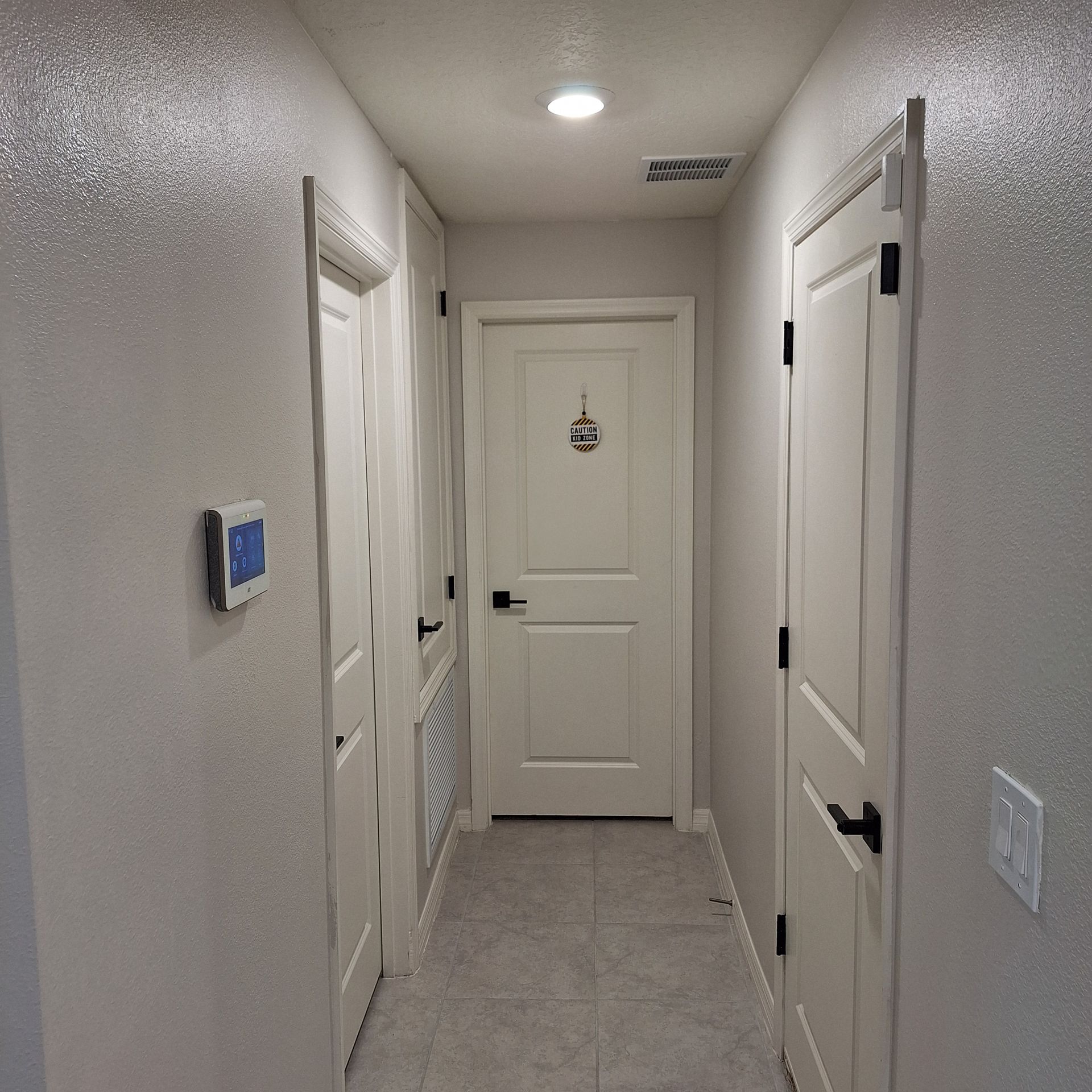 A hallway with white doors and a light on the ceiling