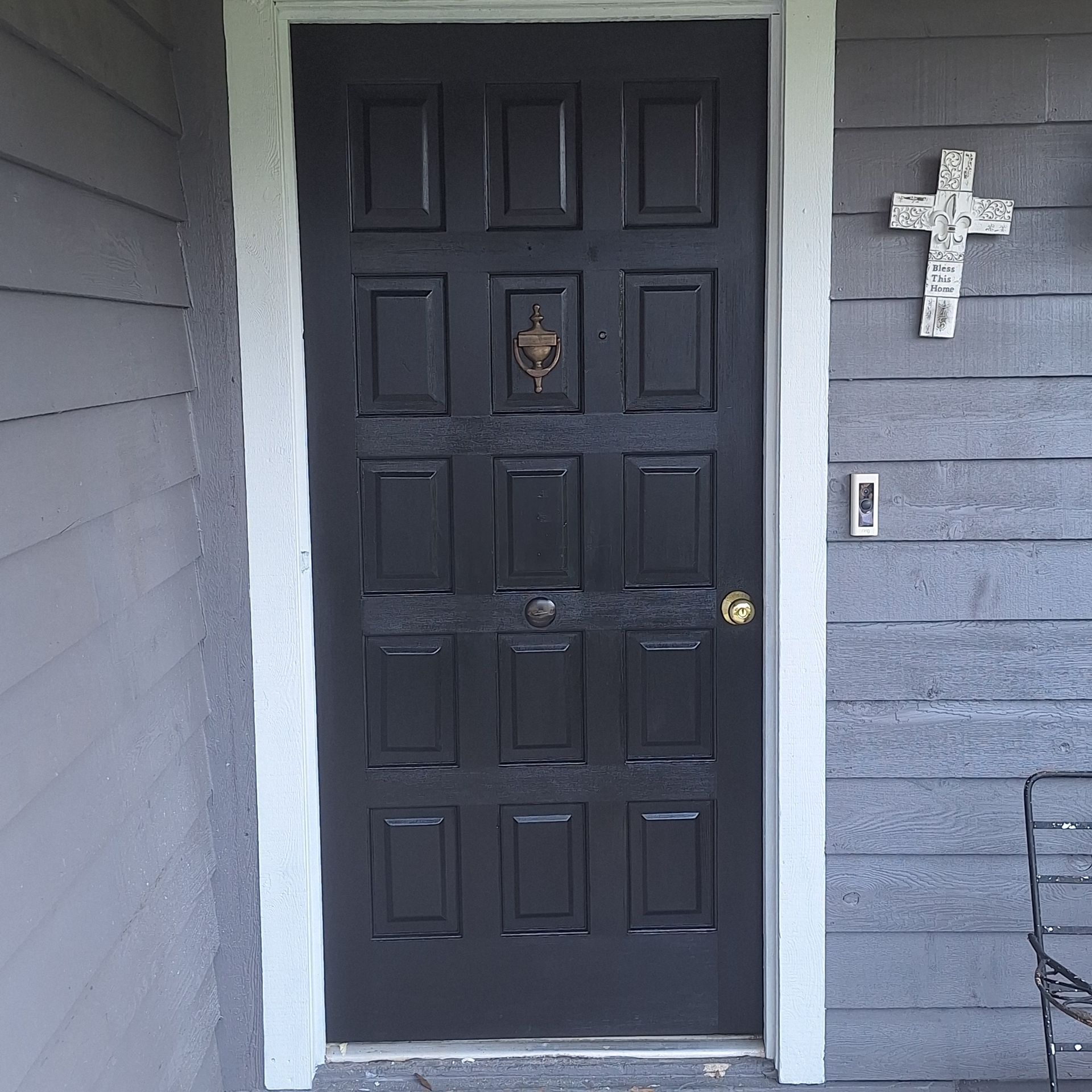 A black door with a cross on the wall above it