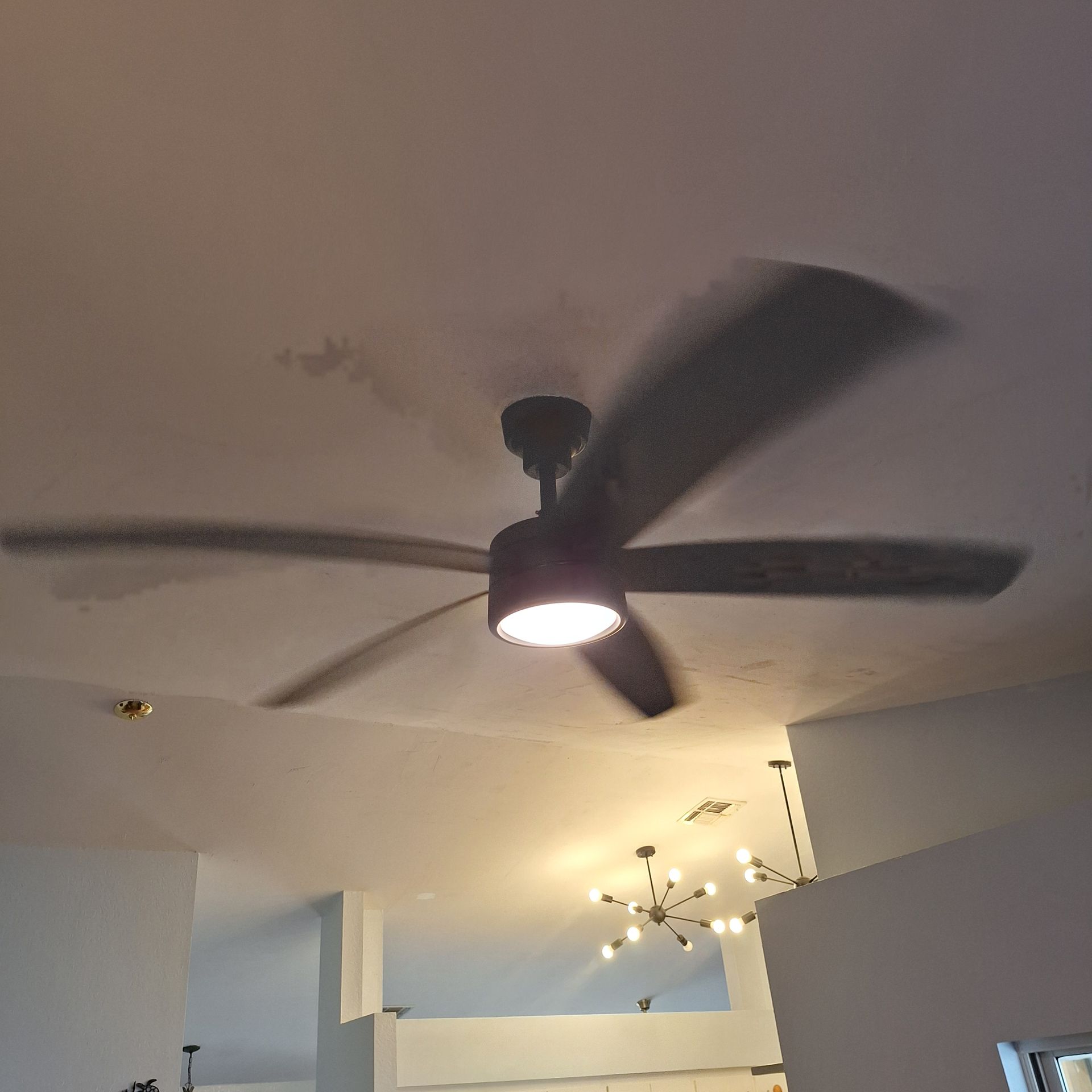 A ceiling fan is spinning in a room with a light on it.