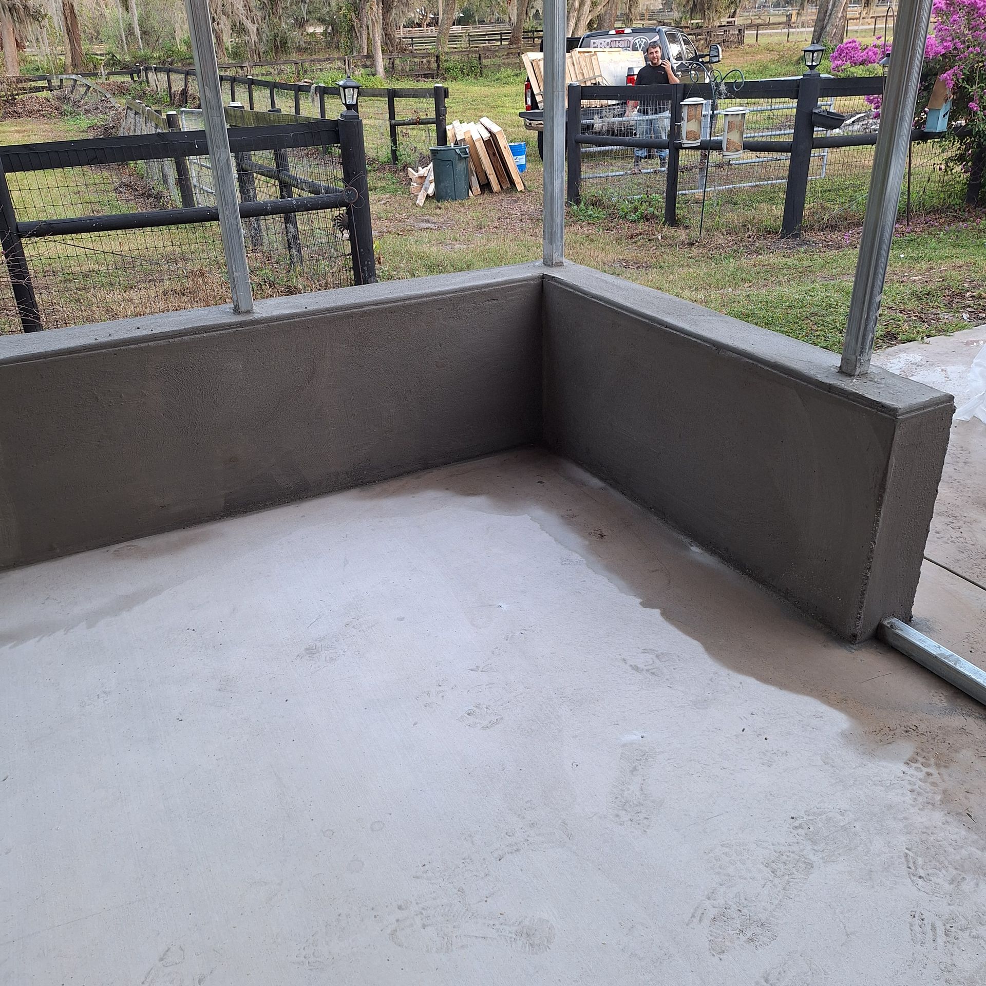 A concrete patio with a fence in the background