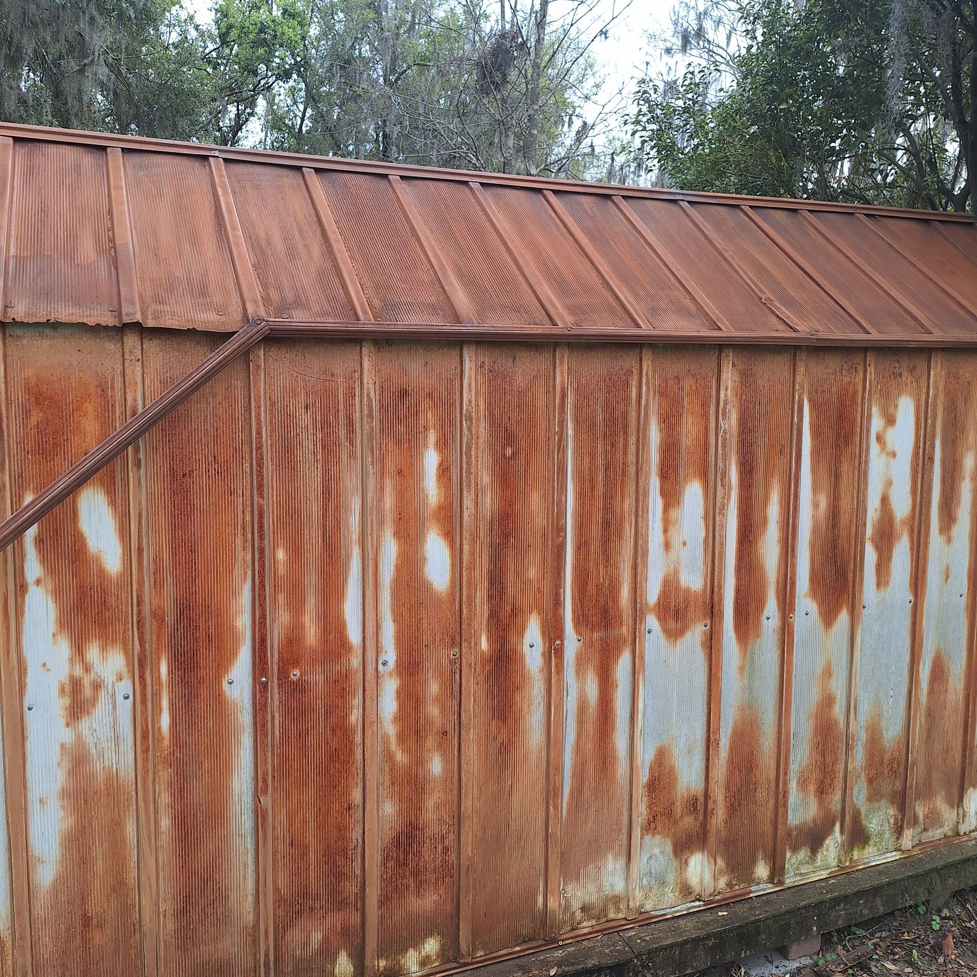 A rusty metal shed with a wooden roof