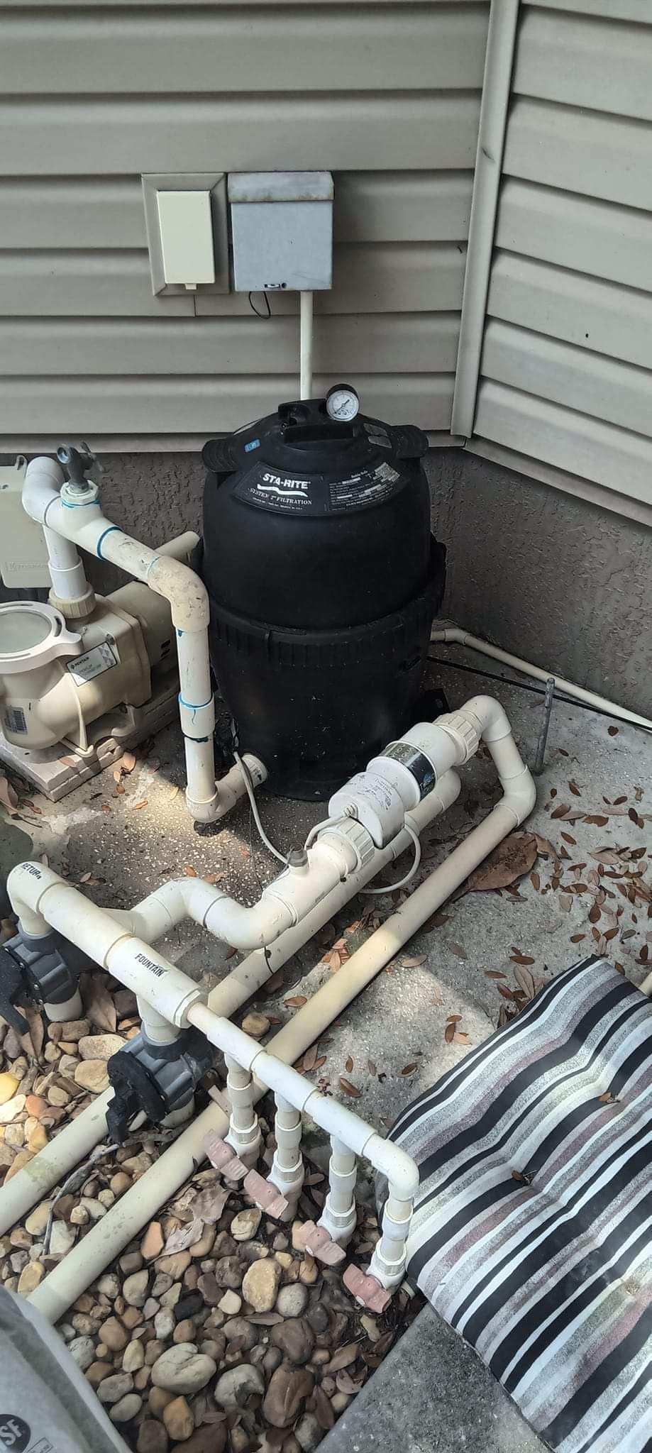 A swimming pool filter is sitting on the ground next to a house.