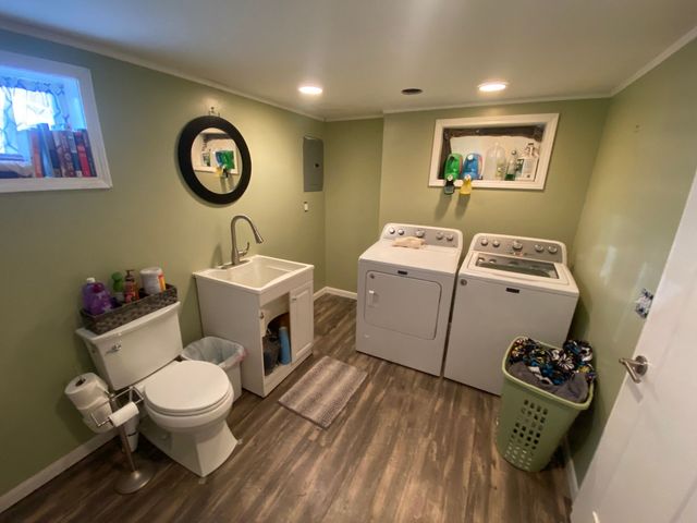 Small laundry room bathroom with toilet, sink, two washers, and green walls.